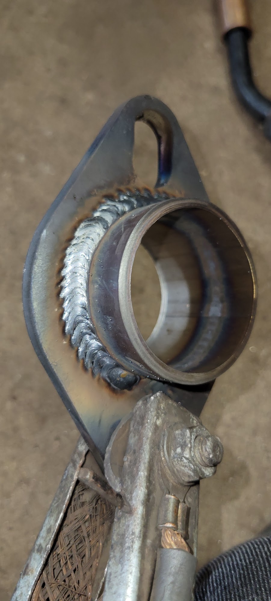 Close-up of a precision weld bead on an exhaust flange