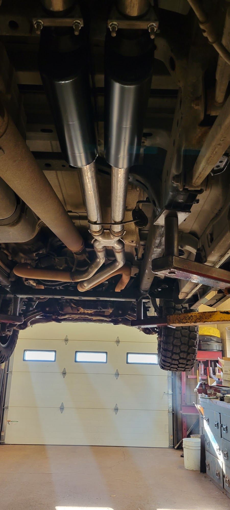 Custom dual exhaust system with new mufflers installed underneath a vehicle on a lift